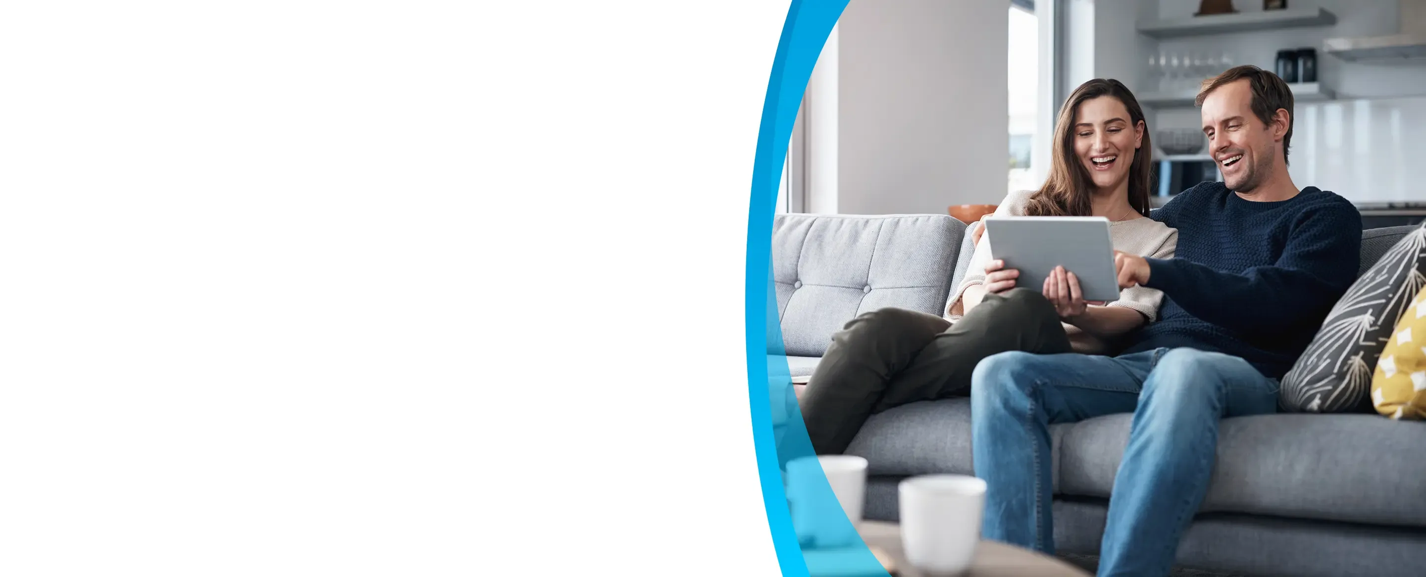 couple sitting on the sofa together and using a tablet